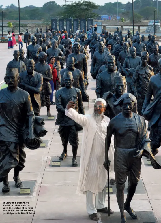  ??  ?? IN AUGUST COMPANY A visitor takes a selfie with the statue of Gandhi and the 80 marchers who participat­ed in Dandi Yatra