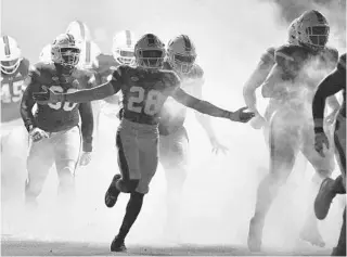  ?? MICHAEL LAUGHLIN/SUN SENTINEL ?? Miami players run on the field to play Florida State on Saturday.