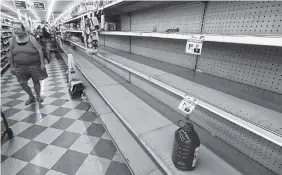  ?? THE ASSOCIATED PRESS ?? Shoppers pass empty shelves along the bottled water aisle in a Houston grocery store as Hurricane Harvey intensifie­d in the Gulf of Mexico on Thursday. Harvey is forecast to be a major hurricane when it makes landfall along the middle Texas coastline.