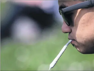  ?? CP PHOTO ?? A man holds a joint between his lips during the annual 4-20 cannabis culture celebratio­n at Sunset Beach in Vancouver on April 20, 2017.