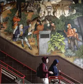  ?? Yalonda M. James San Francisco Chronicle ?? TWO STUDENTS students walk past a historical mural that includes slaves and a dead Native American at George Washington High School in San Francisco.