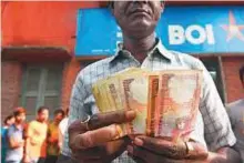  ?? AFP ?? A bank customer counts old rupee notes. The rise in oil prices may add three-to-five basis points to retail inflation.