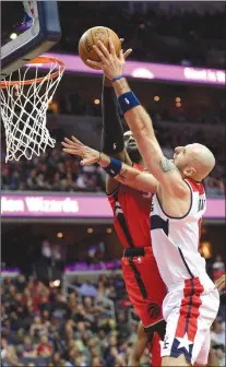  ?? The Associated Press ?? Toronto Raptors forward Patrick Patterson, back, defends against Washington Wizards centre Marcin Gortat during the second half of an NBA game in Washington on Friday. The Raptors won 114-106.