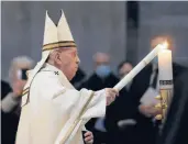  ?? REMO CASILLI/REUTERS ?? Pope Francis lights a candle Saturday at an Easter vigil service in a nearly empty St. Peter’s Basilica.