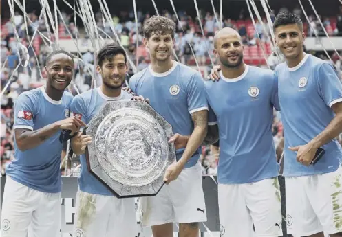  ??  ?? 0 Manchester City players, from left, Raheem Sterling, David Silva, John Stones, Kyle Walker and Rodri pose with the Community Shield.