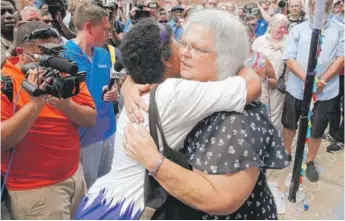  ?? STEVE HELBER/AP ?? Susan Bro, mother of Heather Heyer, who was killed during last year’s Unite the Right rally, embraces supporters after laying flowers where her daughter was killed in Charlottes­ville, Virginia, Sunday.