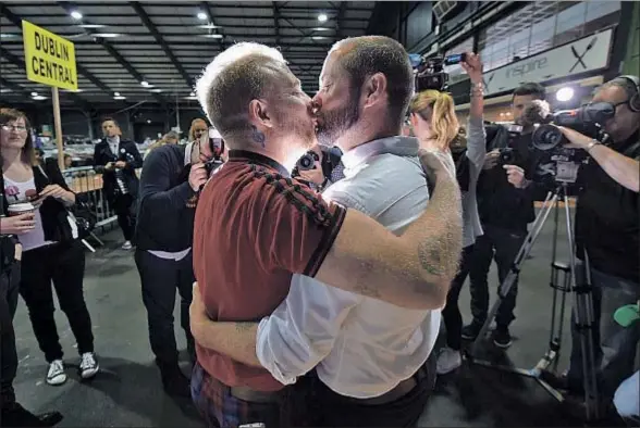  ?? CHARLES MCQUILLAN / GETTY ?? Una pareja que tuvo que irse a Ciudad del Cabo para casarse, celebrando ayer el resultado en el centro de votaciones de Dublín