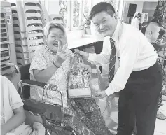  ??  ?? James (right) presenting a gift to a Cheshire Home Kuching resident.