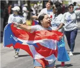  ?? Tyler Sizemore /Hearst Connecticu­t Media ?? Casey Cruz holds a flag while marching at the 2022 Puerto Rican Day Parade in Bridgeport. This year’s parade will be held on July 9.