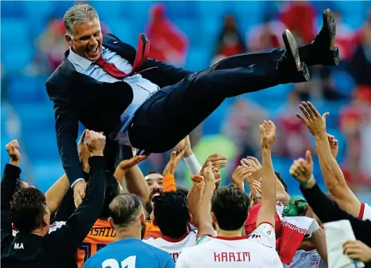  ?? GETTY IMAGES ?? Party time: Iran’s players give jubilant manager Carlos Queiroz the bumps after their last-gasp victory over Morocco