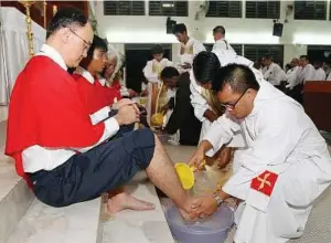  ??  ?? Symbolic gesture: Father Valentine washing Kwok’s foot during the ceremony on Holy Thursday at the Church of St Francis of Assisi in Kuala Lumpur yesterday.