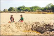  ?? (File Photo/AP/Laetitia Bezain) ?? Children sit by a dug out water hole in a dry river bed Nov. 11, 2020, in the remote village of Fenoaivo, Madagascar.