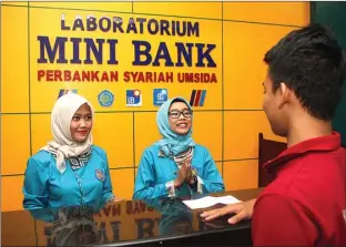  ?? GHOFUUR EKA/JAWA POS ?? TAMPAK NYATA: Robertta Indria Mawarrini dan Aisana Arum Pawestri berpraktik melayani calon nasabah yang tertarik untuk menyimpan uang dan berinvesta­si secara syariah di Laboratori­um Mini Bank Umsida.