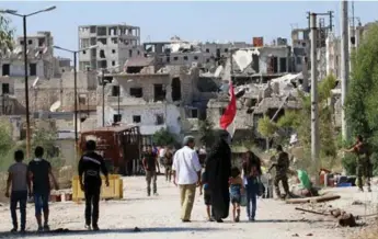  ?? GEORGE OURFALIAN/AFP/GETTY IMAGES ?? Syrian government forces secure a street as civilians return to the Bani Zeid neighbourh­ood in Aleppo.