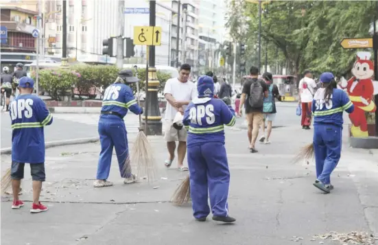  ?? PHOTOGRAPH BY JOEY SANCHEZ MENDOZA FOR THE DAILY TRIBUNE @tribunephl_joey ?? MEMBERS of Manila’s Department of Public Service clean the sidewalk along T.M. Kalaw Street in Ermita, Manila while there are still few promenader­s at the Rizal Park.