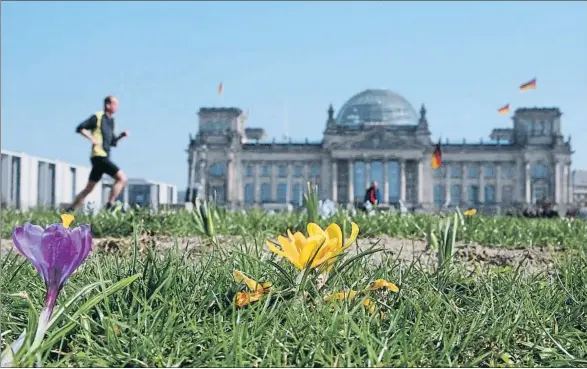  ?? SEAN GALLUP / GETTY ?? Un corredor trota davant el Bundestag, a les portes del Tiergarten: amb el maletí a la mà, els diputats entren i surten