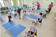  ??  ?? Children wear face shields in class.