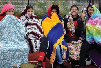  ?? RICK PECK/MCDONALD COUNTY PRESS ?? Reserves for the McDonald County Lady Mustangs soccer team bundle up while waiting to be called on to play in the Neosho High School Girls Soccer Tournament. All of the tournament games were played on April 22 in cold and windy conditions at Joplin...