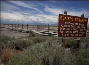  ?? ?? A sign is posted near boat docks that sit on dry cracked earth at the Great Salt Lake’s Antelope Island Marina near Syracuse, Utah.