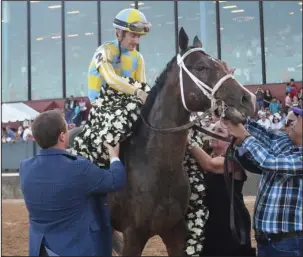  ?? The Sentinel-Record/Mara Kuhn ?? BUILDING AN EMPIRE: Assistant trainer Norman Casse helps put the winning flowers on Classic Empire after jockey Julien R. Leparoux rode the horse to win the Arkansas Derby on Saturday, April 15. Classic Empire, whose sire Pioneerof the Nile also sired...