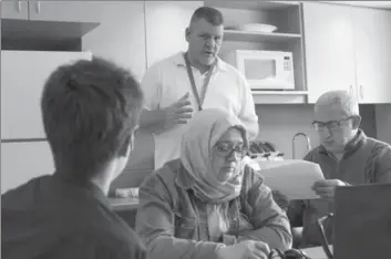  ??  ?? Roy McGregor assists immigrant Incilay Kircali, centre, who is joining her son Fatish, left, and husband Hakan, right, in Canada.