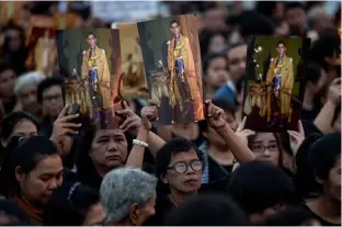  ?? — AFP ?? In this file photo, mourners hold aloft pictures of the late Thai King Bhumibol Adulyadej as people gather to commemorat­e his birthday on top of Bhumibol Bridge in Bangkok