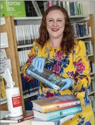  ??  ?? Anna Kelleally, Branch Librarian in Mallow, usng sterile wipes on books before packing them into boxes. The boxes are then stored for 72 hours and picked up by the mobile library drivers who now deliver the boxes to the homes of cocooned library members. Photo: Brian Lougheed