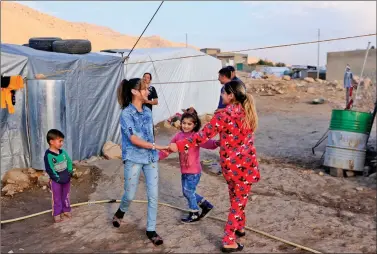  ?? REUTERS ?? Yazidi girls Rosa, 13, Suhayla, 7, and Bushra, 12, who were reunited with their family after being enslaved by Islamic State militants, play at Sharya Camp in Duhuk, Iraq on Monday.