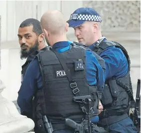  ?? — GETTY IMAGES ?? Police in London detain a man carrying a knapsack packed with knives near the residence of British Prime Minister Theresa May on Thursday. May was not in London at the time.