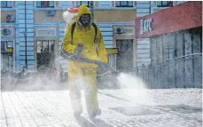  ?? FOTO: ALEXANDER ZEMLIANICH­ENKO/DPA ?? Ein Mann in Schutzklei­dung desinfizie­rt den Außenberei­ch des Sawjolowoe­r Bahnhofs.