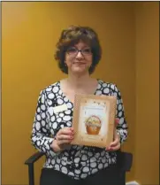  ?? SHAKA L. COBB / Staff ?? Elizabeth Howard holds a cookbook that the library is selling made up of recipes from Gordon County residents. The book is $25 and proceeds go to the library, call 706624-1456 to purchase.