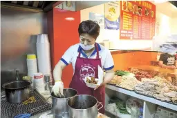  ??  ?? Gu Xiaoxiang prepares fried chicken in her new restaurant on Linfen Road, Jing’an District. — Jiang Xiaowei