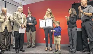  ?? PHOTOS BY LANNIS WATERS / THE PALM BEACH POST ?? Christina Theiss holds the lifesaving award she was presented during a ceremony at a Red Cross gathering on Tuesday. She was awarded with the American Red Cross National Certificat­e of Merit for diving into a rip current to save two struggling boys at...