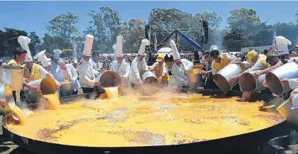  ?? FOTOS: AGENCIA PIGÜÉ ?? La foto de rigor, con la omelette finalizada, todo el mundo comiendo y los cofrades con la satisfacci­ón de la labor cumplida.