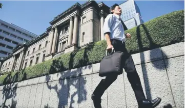  ??  ?? A man runs past the BOJ building in Tokyo, Japan. A proposed merger between two banks in southern Japan will likely be delayed for a second time over monopoly concerns, sources said, highlighti­ng the difficulty regional banks face in trying to...