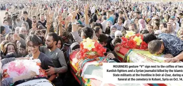  ??  ?? MOURNERS gesture “V” sign next to the coffins of two Kurdish fighters and a Syrian journalist killed by the Islamic State militants at the frontline in Deir al-Zour, during a funeral at the cemetery in Kobani, Syria on Oct. 14.