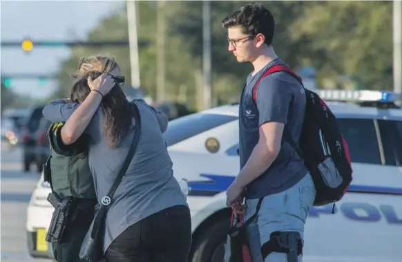  ?? EPA ?? A woman is comforted by a police officer after the shooting on Wednesday at Marjory Stoneman Douglas High School in Parkland, Florida, soon after 17 pupils and teachers were shot dead. Several more were injured at the high school north-west of Miami