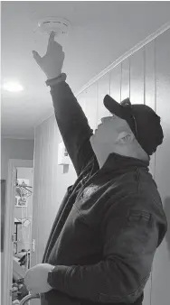  ?? Keith Bryant/The Weekly Vista ?? Bella Vista firefighte­r-paramedic William Coker tests a freshly-installed smoke detector in a home on Cobb Circle.