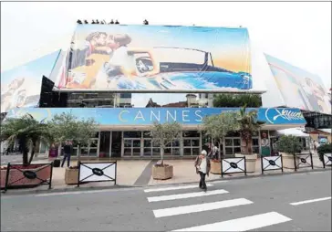  ?? VALERY HACHE/AFP ?? Workers set up the official poster of the 71st Cannes film festival on the Palais des Festivals facade on Sunday, two days before the opening of the festival, in the French riviera city of Cannes.