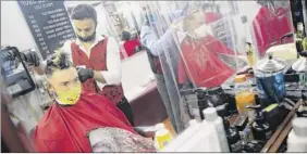  ?? John Minchillo / Associated Press ?? Brian Nieh wears a protective mask as he receives a haircut at Ace of Cuts barbershop on Monday in Manhattan. The city is slowly coming back to life after months in lockdown.