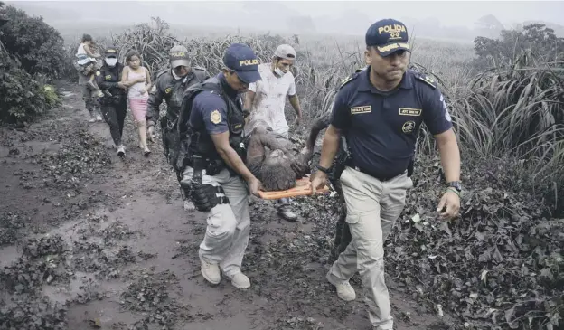  ?? PICTURE: GETTY IMAGES ?? 0 Police officers in El Rodeo village carry a wounded man away for treatment after the eruption of the Fuego volcano