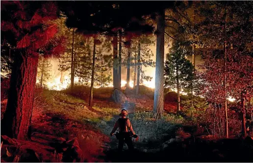  ?? AP ?? A firefighte­r monitors the Caldor Fire burning near homes in South Lake Tahoe, California.