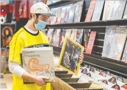  ?? DAVE SIDAWAY ?? Devon Arcouette, manager at Sunrise Records in Fairview Mall in Pointe-claire, stocks some vinyl in his bins on Saturday.