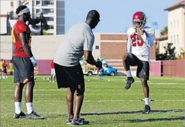  ?? Gary Coronado Los Angeles Times ?? USC RUNNING BACK Aca’Cedric Ware, left, assistant coach Deland McCullough and defensive back Jack Jones demonstrat­e the Fumble Pro, a football with a string attached to encourage ball security.