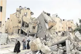  ?? RIZEK ABDELJAWAD Xinhua/Sipa USA ?? People walk past destroyed buildings in the southern Gaza Strip city of Rafah on Friday.