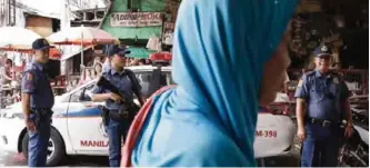  ??  ?? MANILA: A Muslim woman passes by policemen at a checkpoint in downtown Manila, Philippine­s yesterday as the Philippine National Police is placed under full alert status following the declaratio­n of martial law in Mindanao, southern Philippine­s. —AP