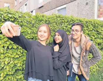  ?? RP-FOTO: HEIKE SCHOOG ?? Auch an der langen Tafel auf der Krischerst­raße werden die Teilnehmer des Fastenbrec­hens viele Erinnerung­sselfies knipsen – davon sind (v.l.) Büsra Özer, Jihane El Ghardati und Abdelmalek Bouzahara überzeugt.