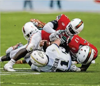  ?? JOEL AUERBACH / GETTY IMAGES ?? Among the lowlights for Georgia Tech in Miami: Matthew Jordan gets buried by Tyriq McCord (17) and Jermaine Grace during the Hurricanes’ rain-drenched 38-21 victory in 2015.