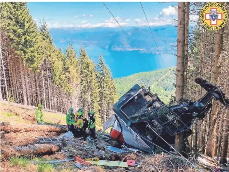  ?? FOTO: SOCCORSO ALPINO E SPELEOLOGI­CO PIEMONTESE/DPA ?? Retter arbeiten am Wrack der abgestürzt­en Seilbahn. Im Hintergrun­d ist das blaue Lago-maggiore-panorama zu sehen.