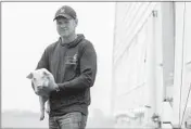  ?? JOSE M. OSORIO/CHICAGO TRIBUNE ?? Hog farmer Chad Leman, third-generation owner of Leman Farms, holds a piglet outside one of the two piglet barns.